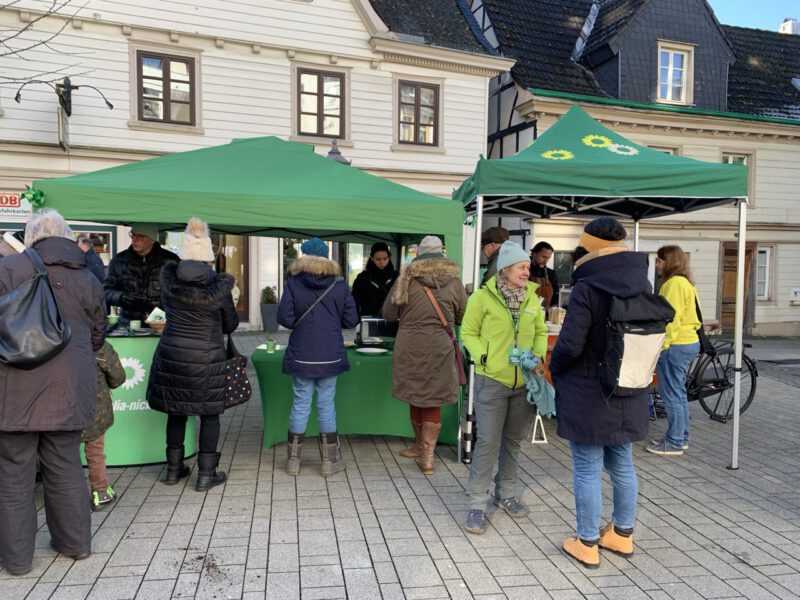 GRÜNER Infostand, zwei Pavillons mit Kaffee und selbstgebackenen Waffeln, davor Menschen